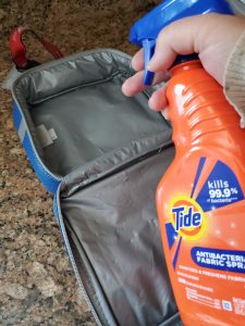 spraying a sanitizing spray on a lunch bag