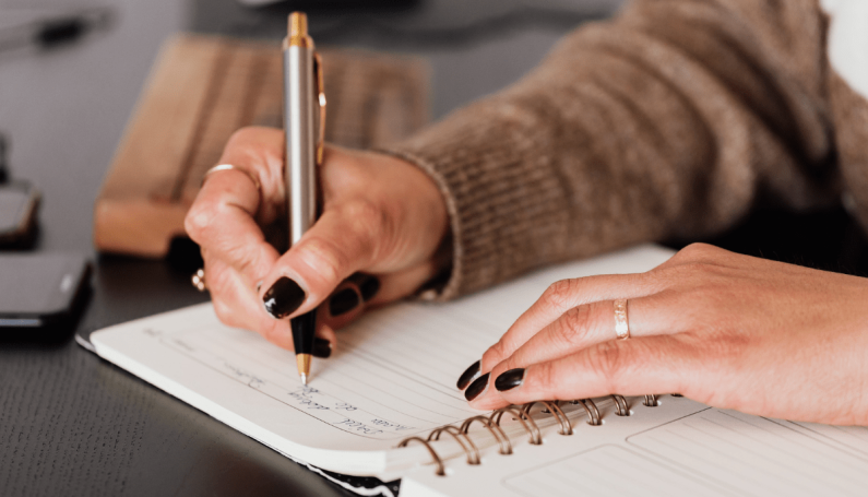 woman writing in a planner (2024 planners for busy moms)