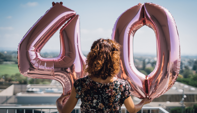 woman holding "40" balloons to celebrate her 40th birthday