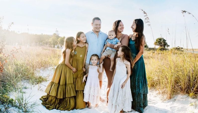 large family with six children standing on the beach
