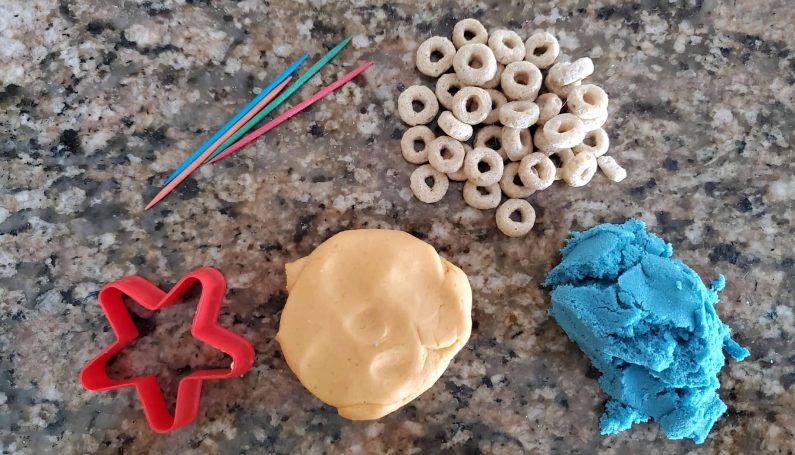 plastic cookie cutter, Cheerios, play dough and kinetic sand