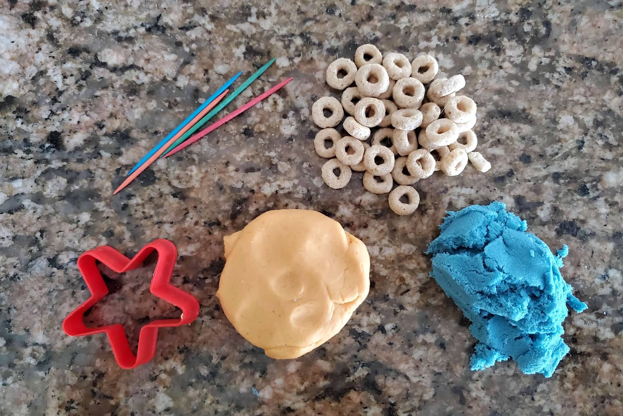 plastic cookie cutter, Cheerios, play dough and kinetic sand
