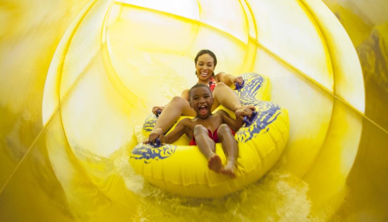 mother and son on a yellow tube sliding down a yellow waterslide at Great Wolf Lodge in Fitchburg, one of New England's indoor water parks