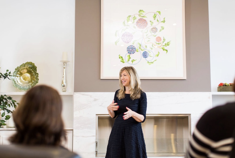 Blonde woman speaks to a group of people at a conference