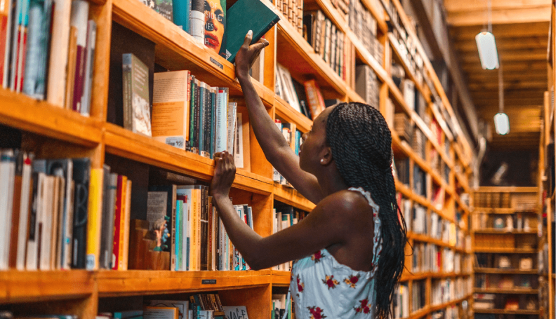 woman pulling book off a bookstore shelf