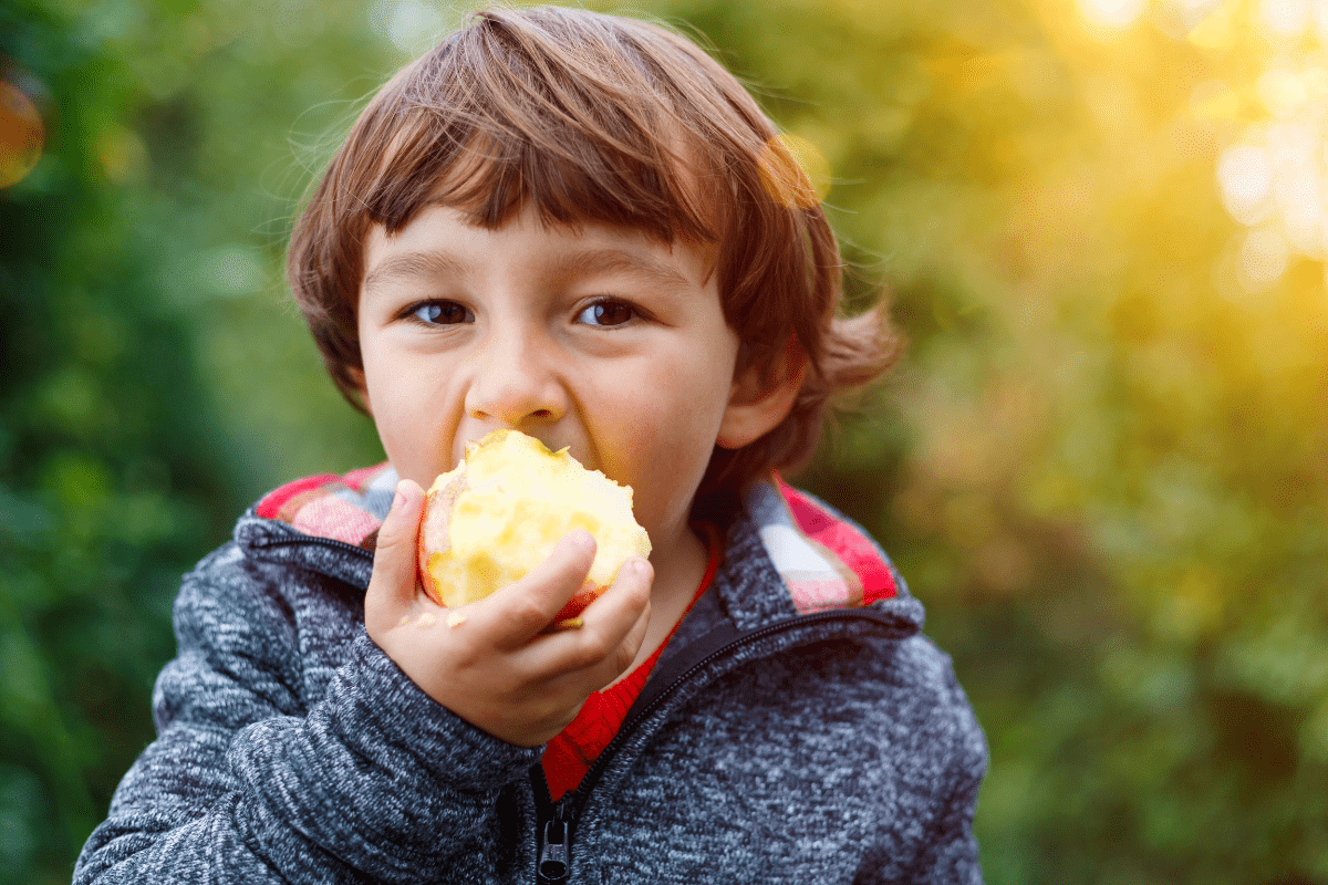 child eating whole apple (artificial ingredients for kids)