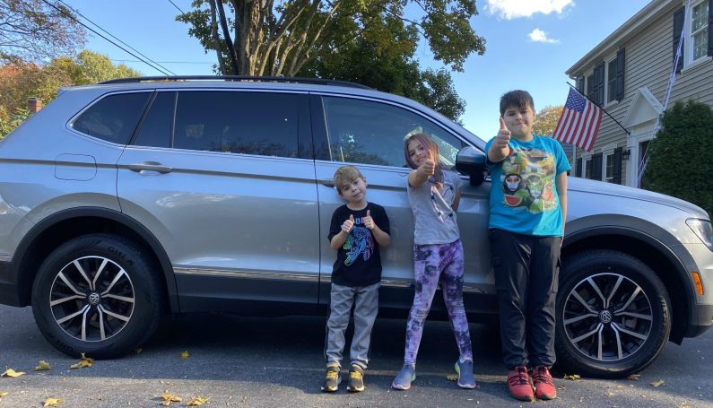 three children standing in front of a Flexcar