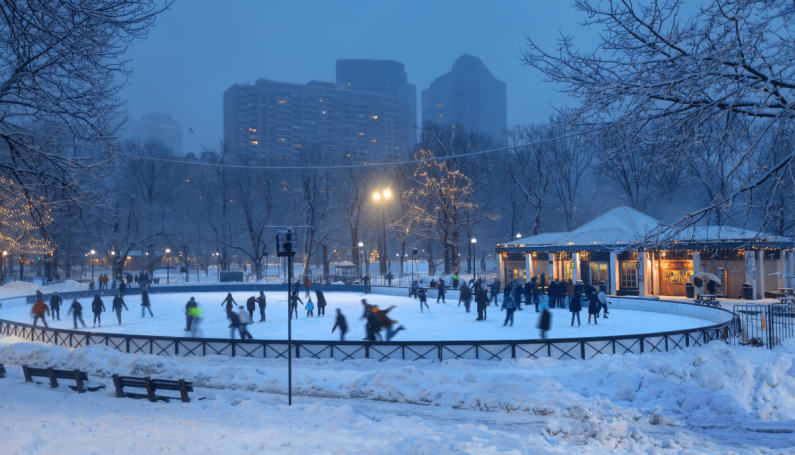 ice skaters skating on Boston Common's Frog Pond at dusk