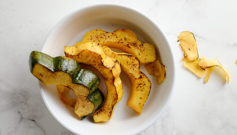 roasted and seasoned slices of acorn squash in a white bowl on a countertop