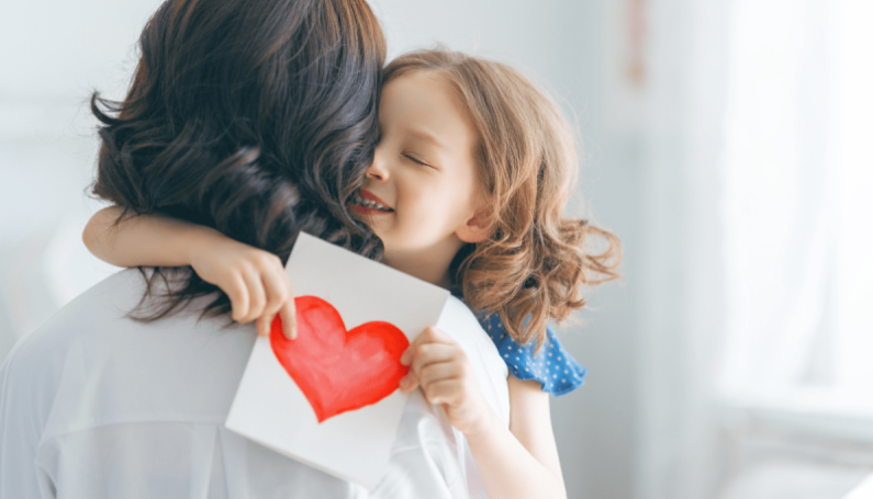 child giving mom a card and hug for Mother's Day