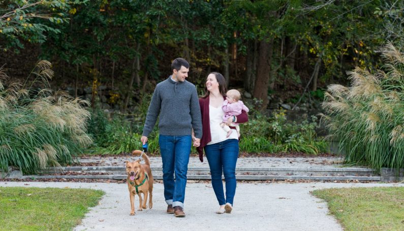 two parents, a baby, and a dog walking together (only child)