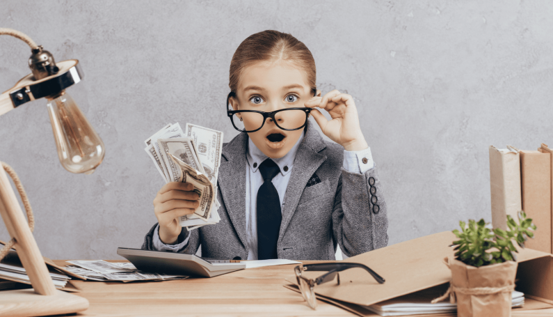 Child, in a business suit with glasses, holding money. She is surprised.