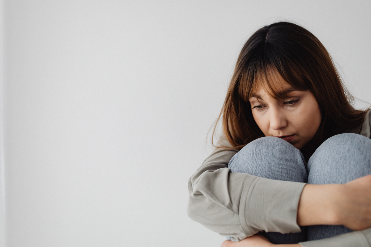 woman hugging knees and looking sad, looking for mom friends but feeling outside the circle