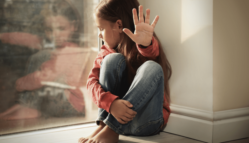 child putting hand out to say "no" and show she does not want a hug