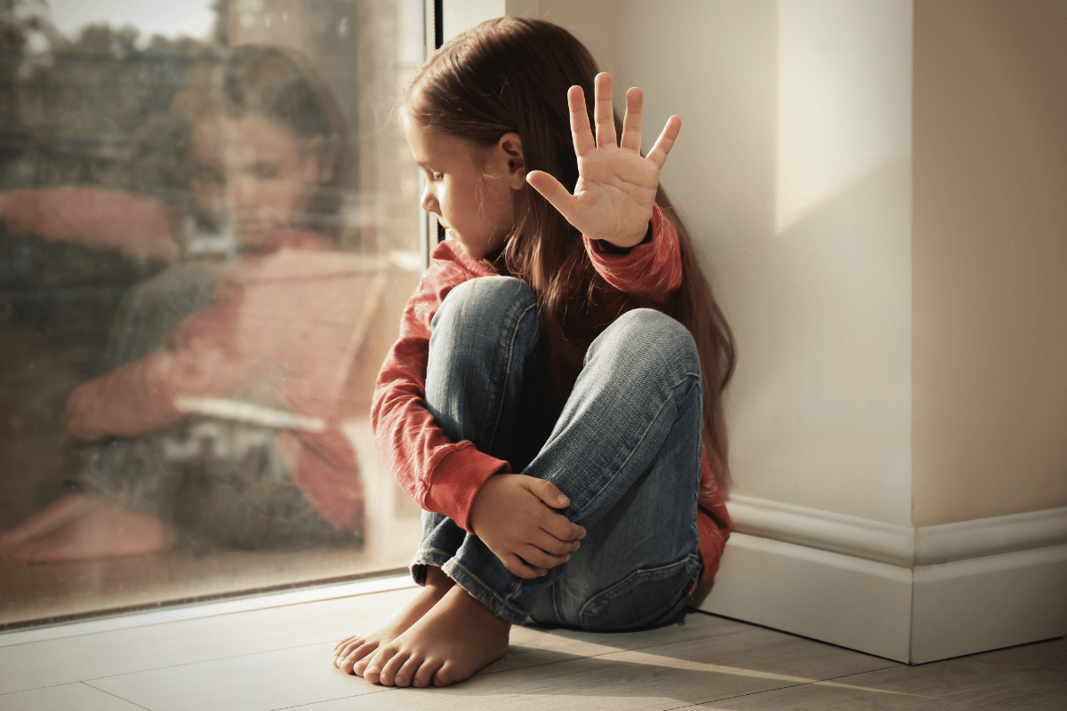 child putting hand out to say "no" and show she does not want a hug