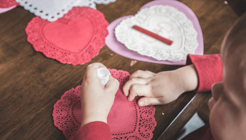 child making a paper valentine (how to celebrate Valentine's Day with kids)