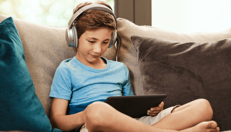child wearing headphones and holding iPad (YouTube channels for kids)