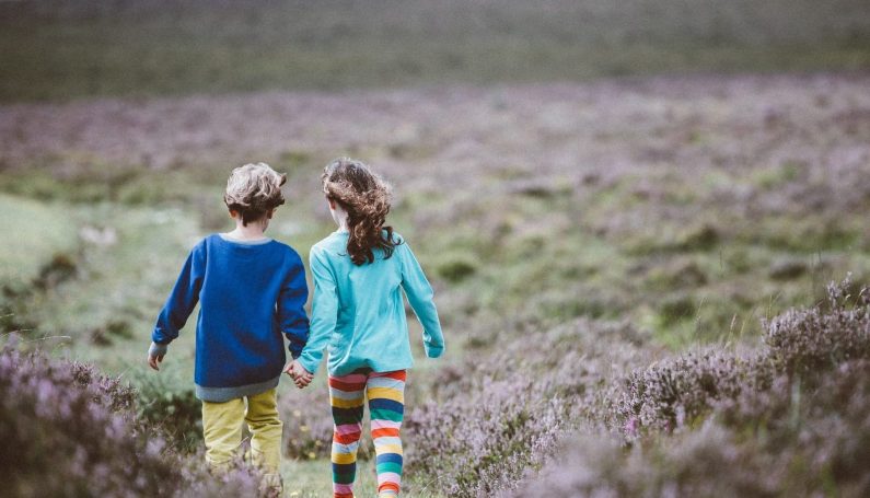 two children holding hands and walking