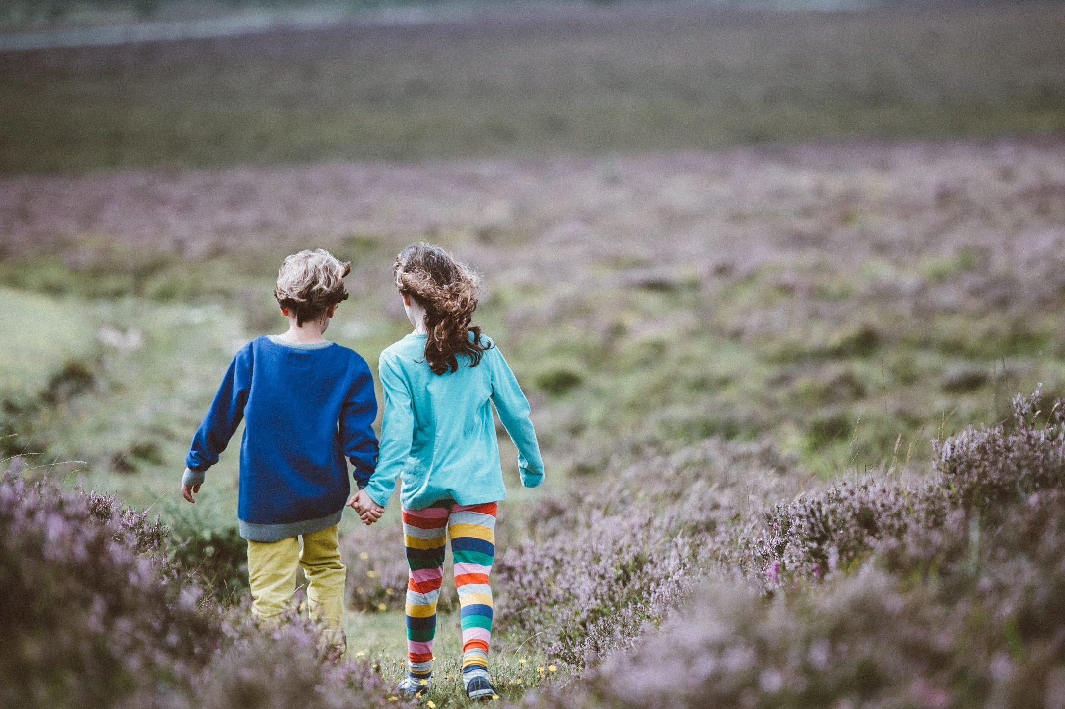 two children holding hands and walking