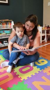 Au pair reading to toddler boy