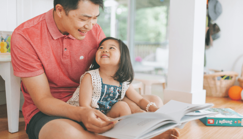 father reading a back-to-school book to his daughter