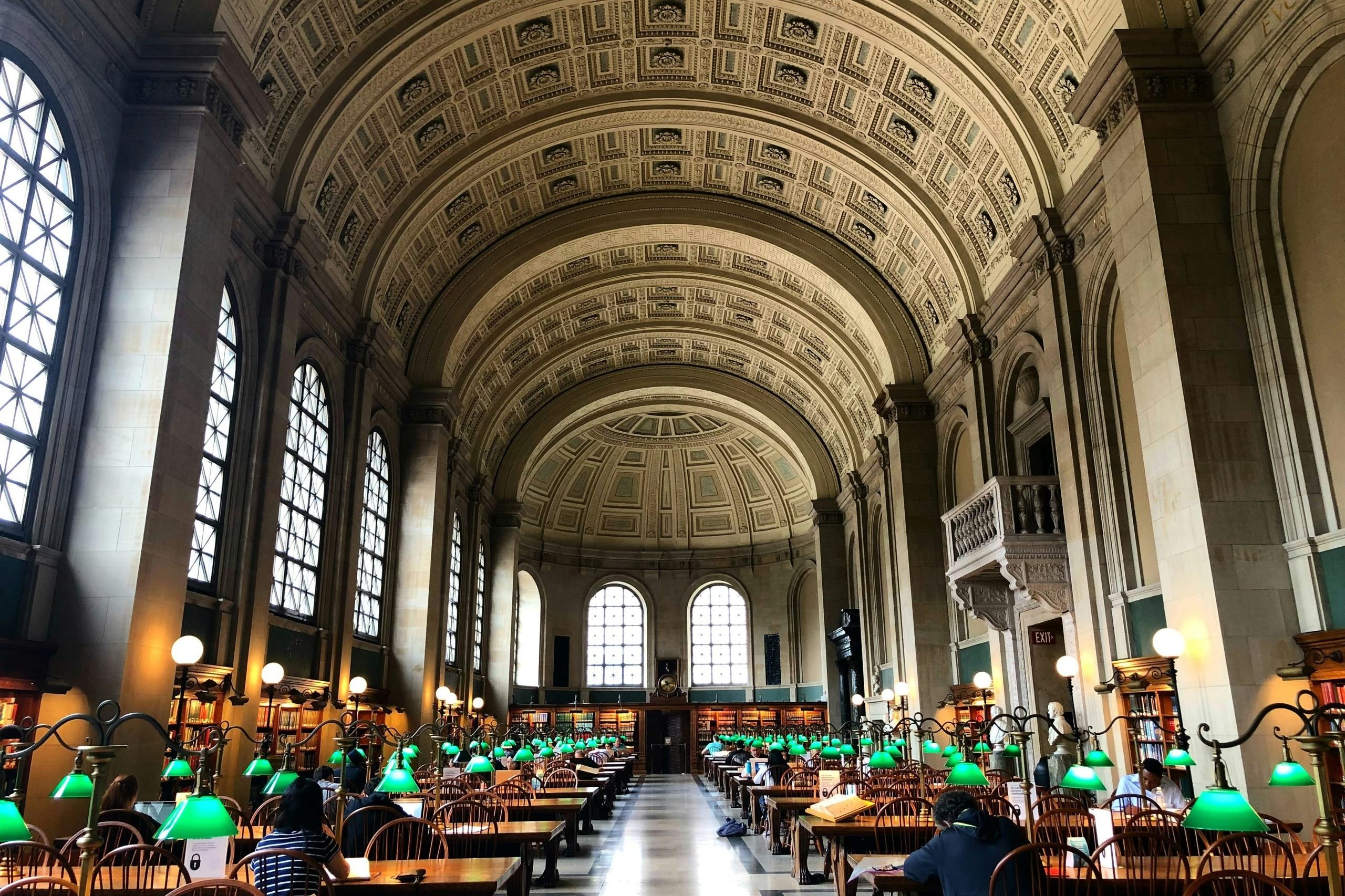 Vast library hall with windows tables and green lamps