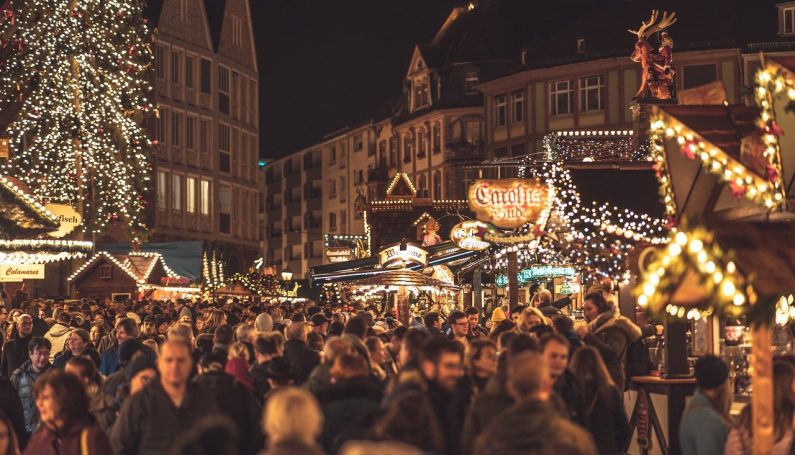 large crowd shopping at an outdoor holiday market at night.