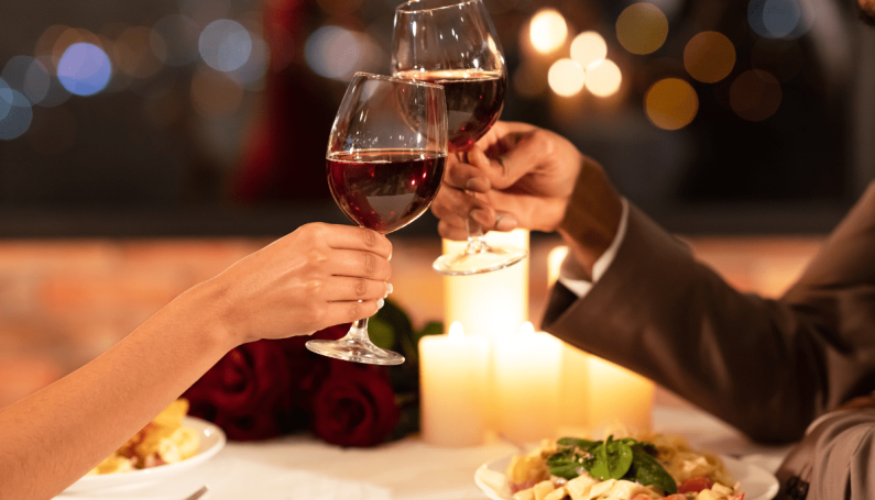 couple holding wine glasses at restaurant (date night restaurants north of Boston)