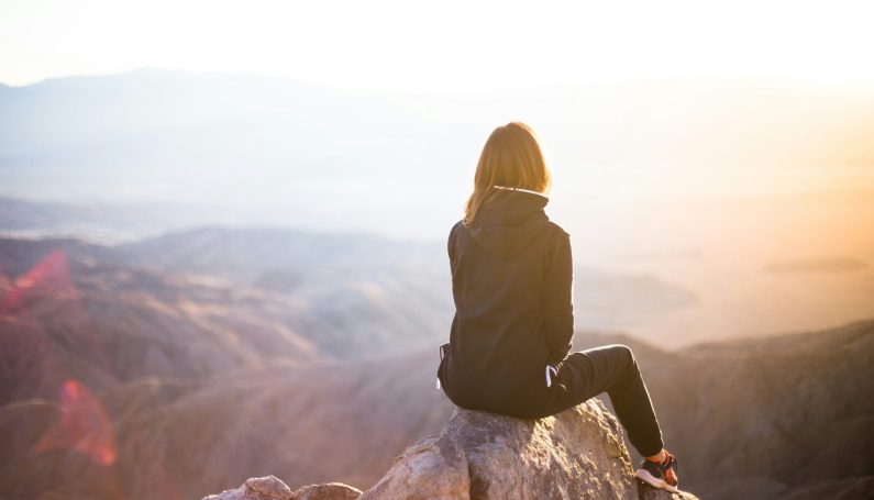 woman sitting on a mountain top (single moms need a break)