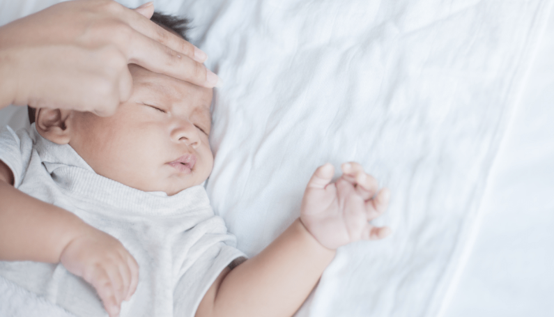 mother checks baby's forehead for fever (febrile seizures)
