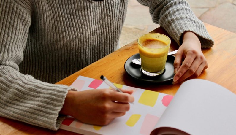woman writing in notebook with cup of coffee (mom's mental load, motherhood)