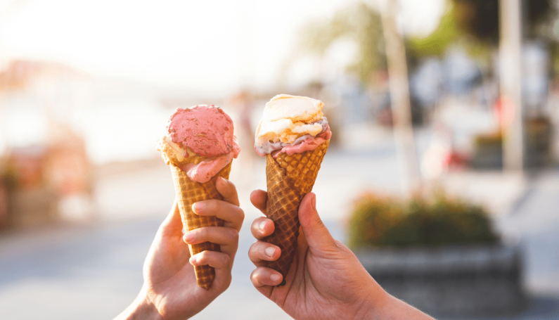 two hands holding two cones of gelato