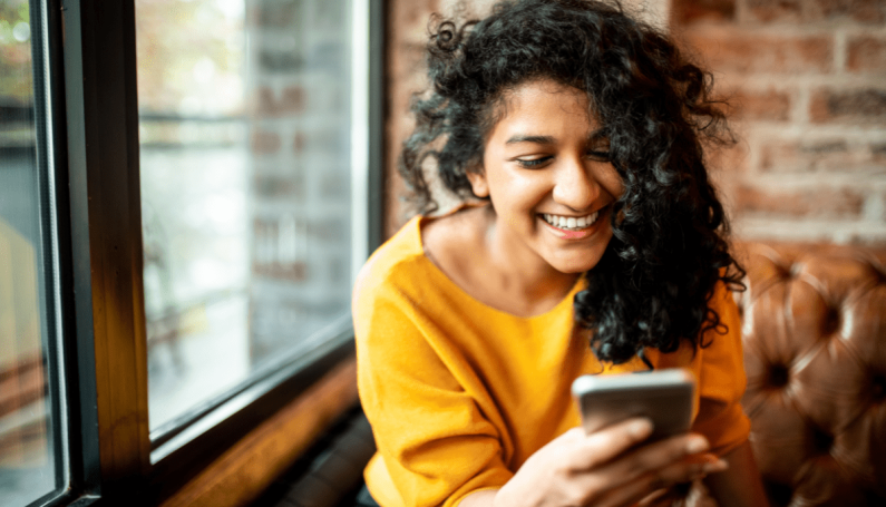 happy woman looking at phone (funny happy Instagram accounts for moms to follow)
