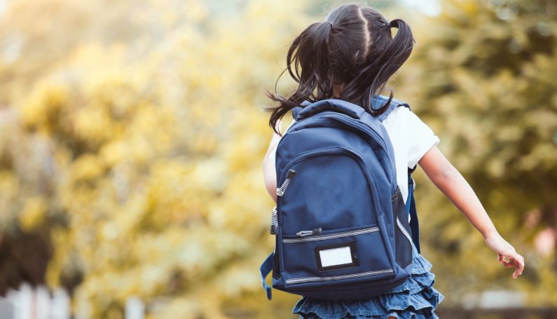 young girl with backpack running to school (hurried child syndrome and mom guilt)