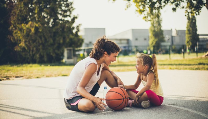 Mother and daughter on playground with basketball (fostering positive body image in girls)