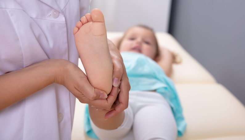 doctor checking child's foot and leg in medical clinic (toxic synovitis)