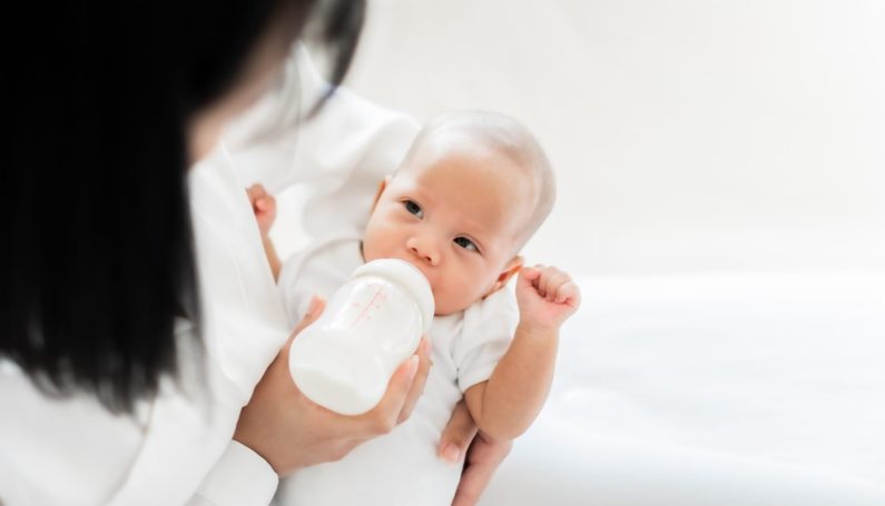 Mother feeding baby with bottle of milk (breastfeeding after breast reduction)