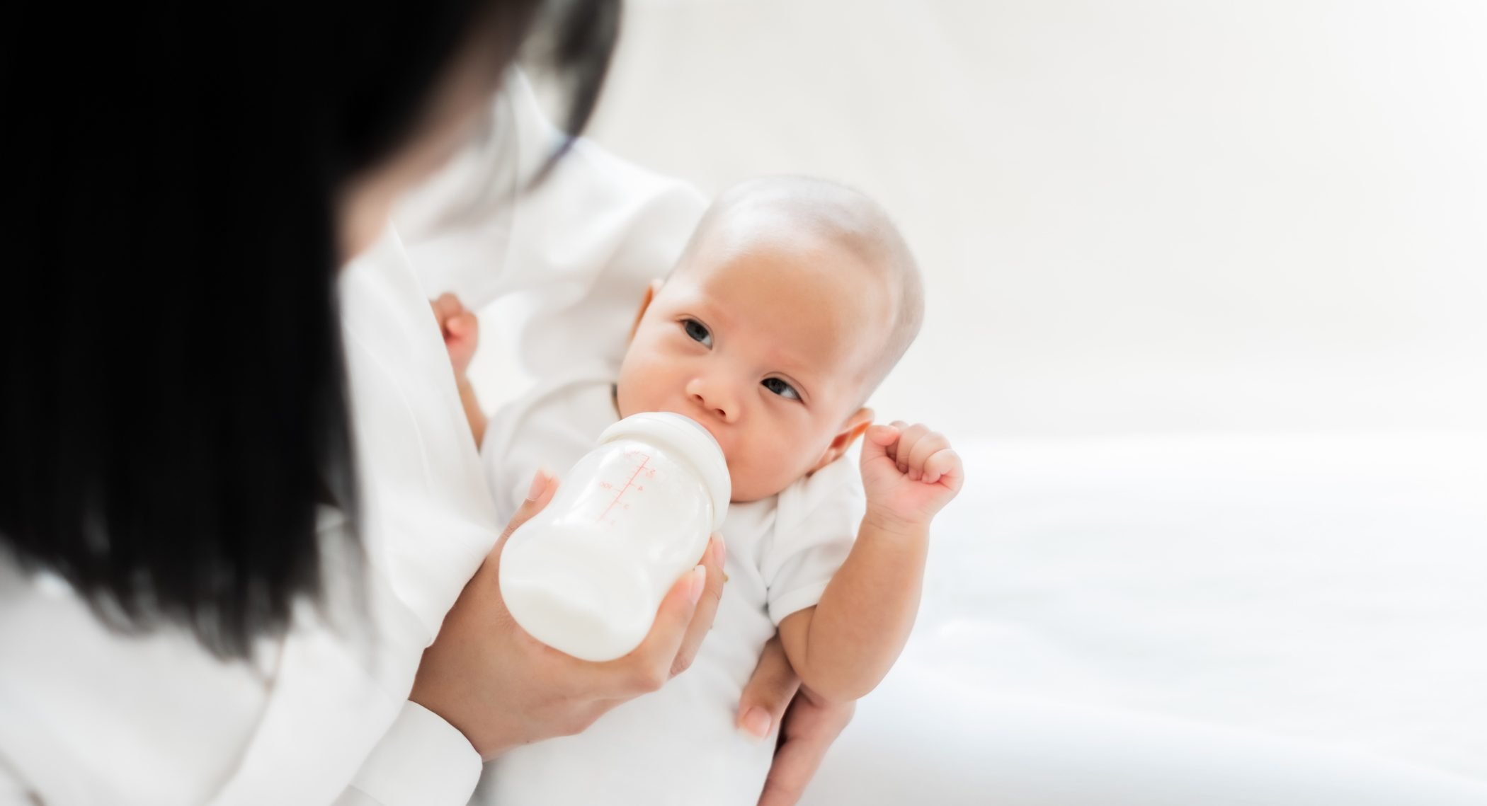 Mother feeding baby with bottle of milk (breastfeeding after breast reduction)
