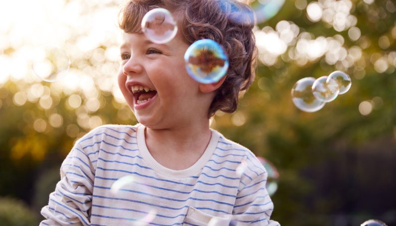young boy having fun in garden chasing bubbles (being a 3-year-old is hard)