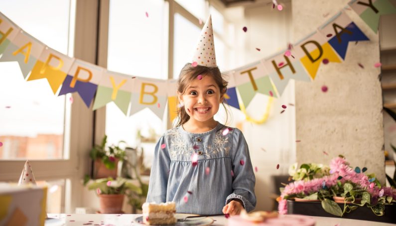 girl celebrating birthday with cake (starting family birthday traditions)