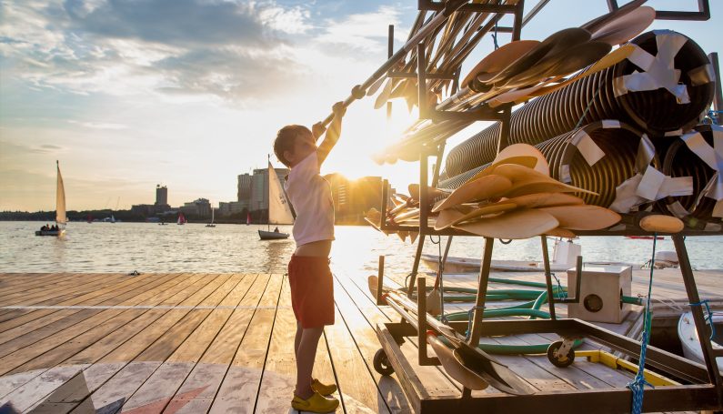 child by sailboats at sunset (things to do in Boston this summer)