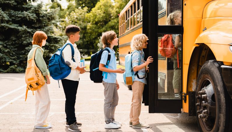 children lined up outside yellow school bus (school bus driver)