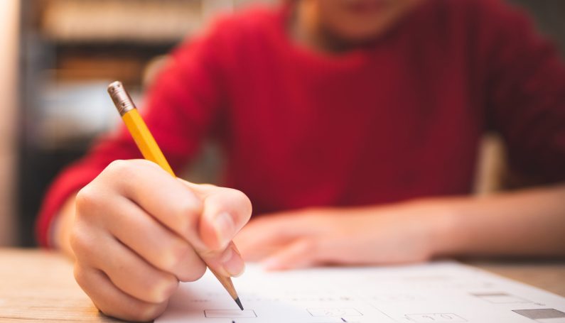 child holding pencil doing homework (kids and goals)