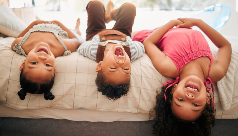 Kids laying upside down on bed (middle child, birth order, three kids)