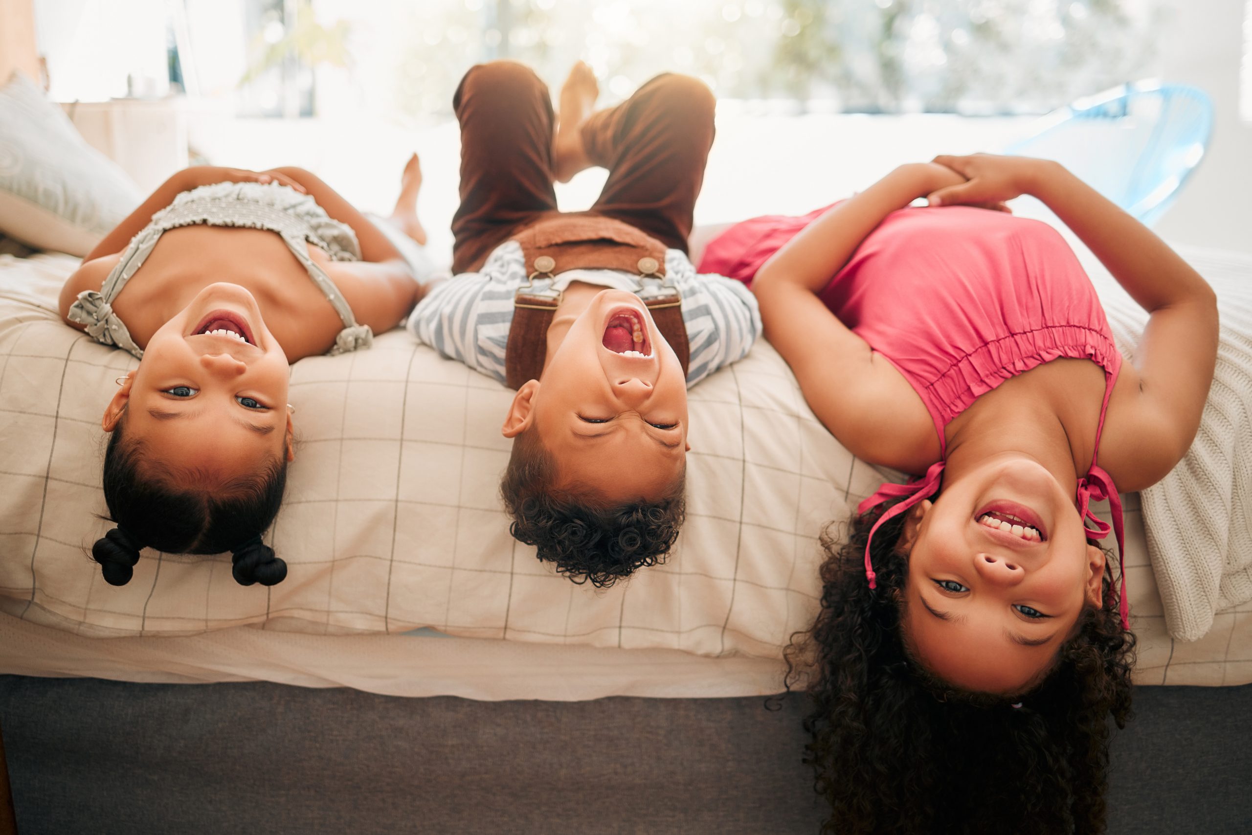 Kids laying upside down on bed (middle child, birth order, three kids)