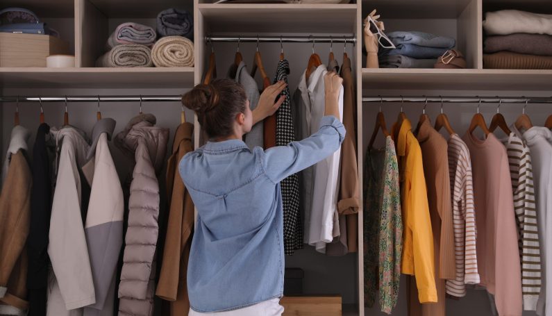 woman choosing clothes from a closet (getting rid of a ton of clothes improved my life)