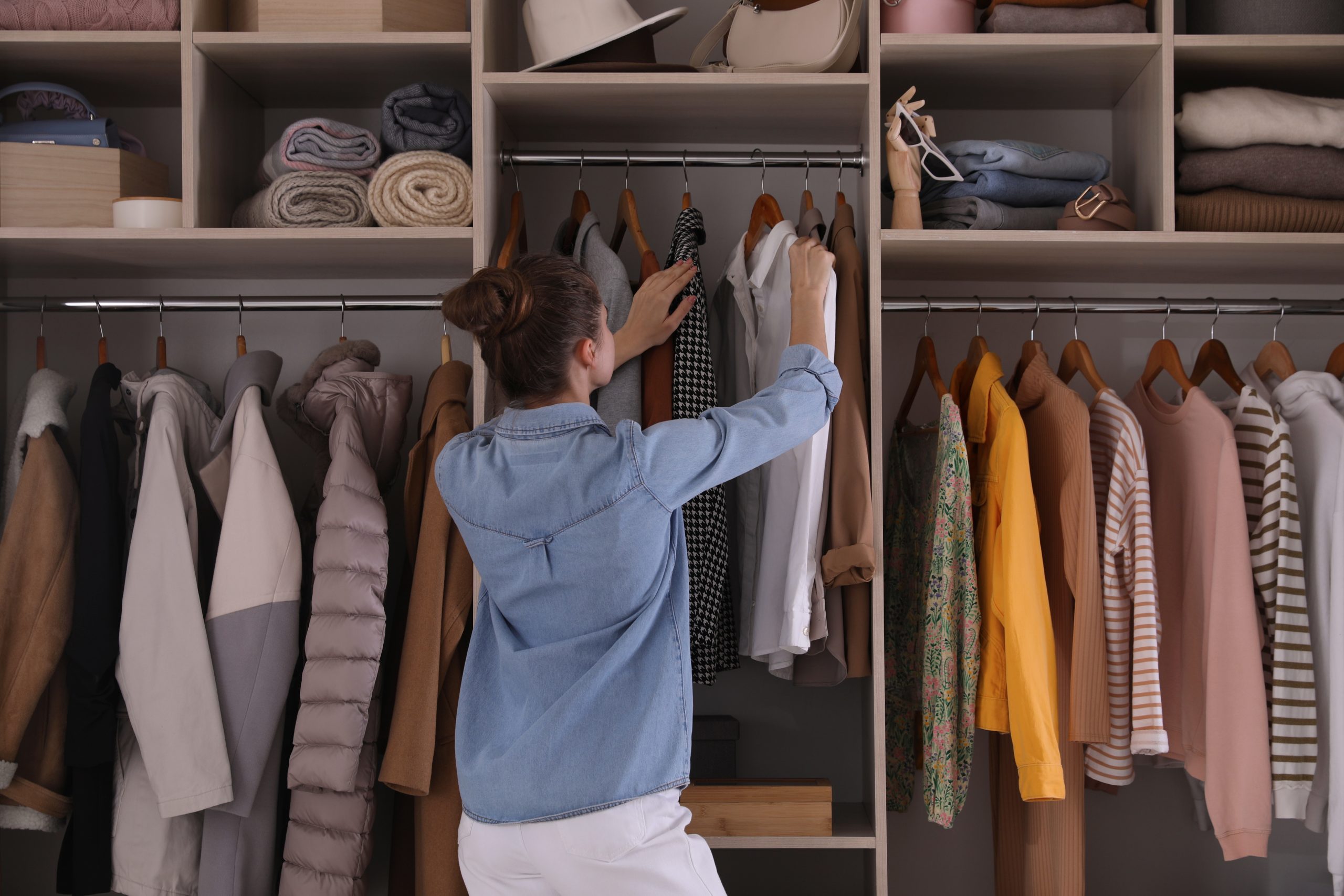 woman choosing clothes from a closet (getting rid of a ton of clothes improved my life)