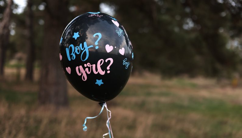 black balloon with "boy? girl?" written on it to show gender reveal (natural gender selection)