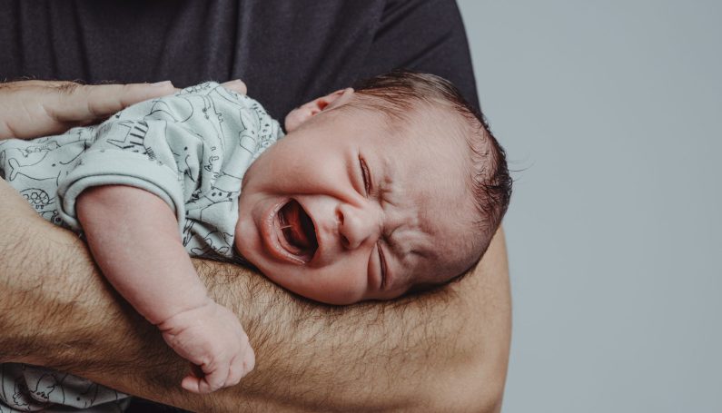 newborn baby lying on father's arm, (newborn period really sucks)