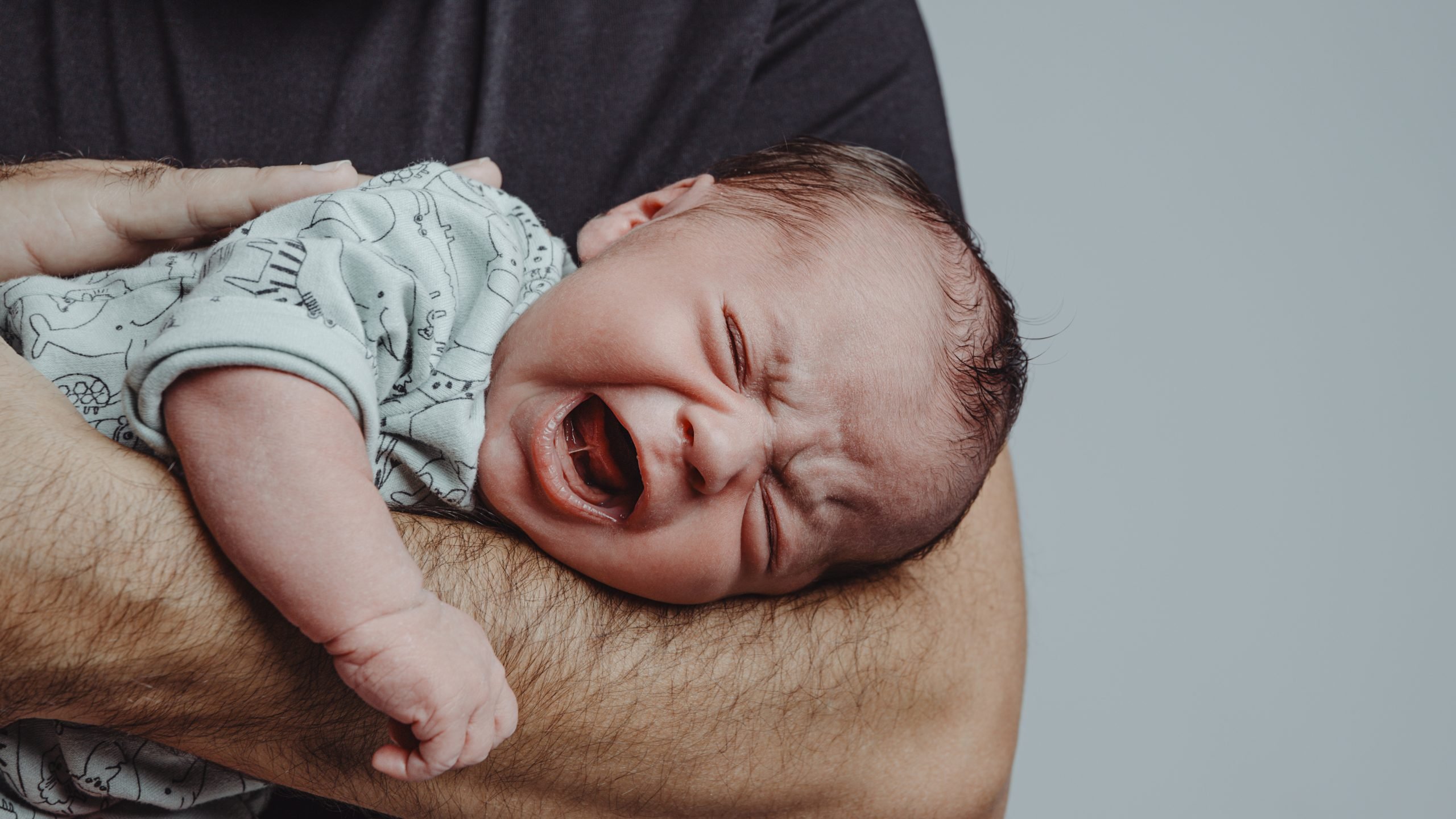 newborn baby lying on father's arm, (newborn period really sucks)
